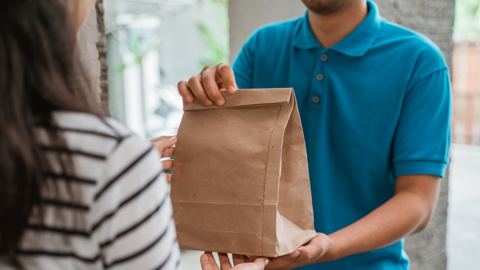 Repartidor entregando un pedido en bolsa de papel kraft reforzada a una cliente en Ecuador.
